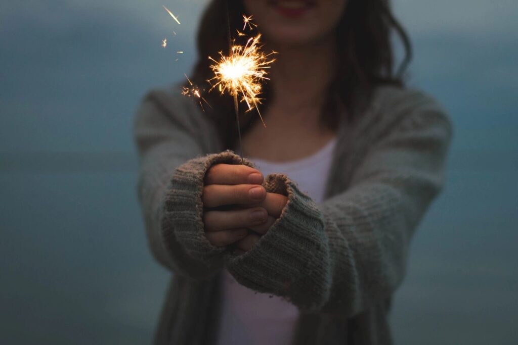 Image of a person holding a sparkler reflects the spark of ideas that can be produced when you engage Seeside Advisory in advertising co-design. 